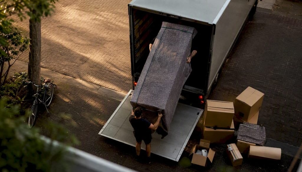 Verhuizers laden de verhuiswagen in met hun handen