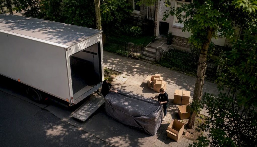 Op een rustige zondag staat er een verhuiswagen in de straat, omringd door dozen en meubels die klaarstaan om ingeladen te worden.
