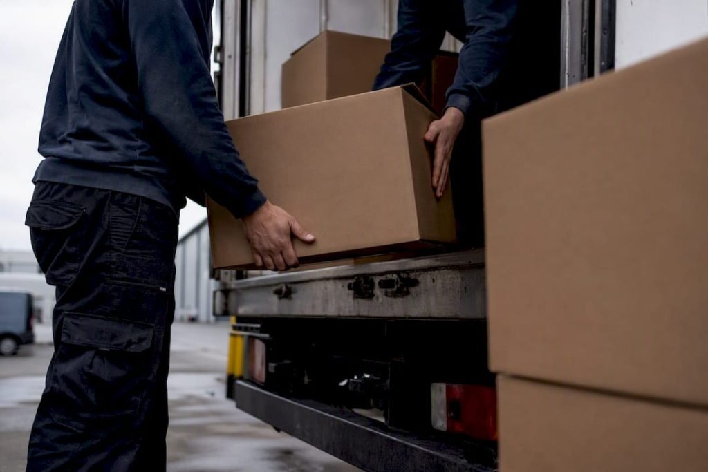 Een team van verhuizers is druk bezig dozen in de vrachtwagen te laden.