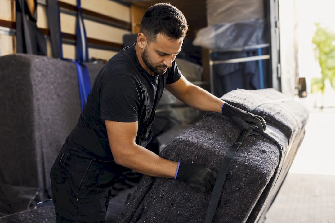Verhuizer die zwaar meubilair in de bestelwagen inpakt