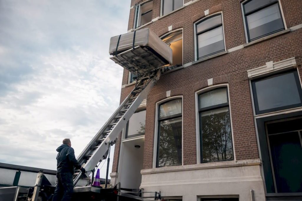 Meubel wordt via het raam met een verhuislift naar boven gebracht