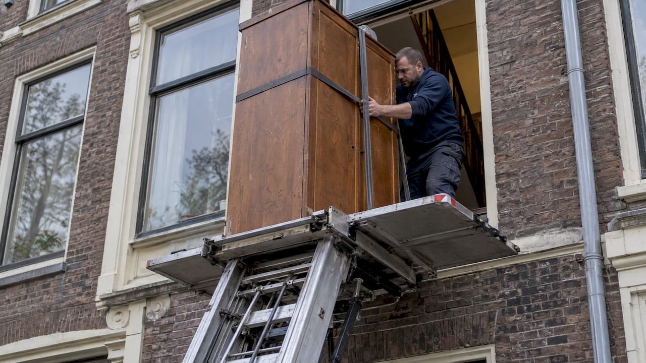 Kledingkast wordt via verhuislift door het raam naar buiten getild